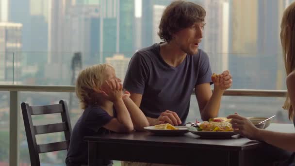 Familia joven desayunando, almorzando en su balcón en un rascacielos con vistas a todo el centro de la ciudad — Vídeos de Stock