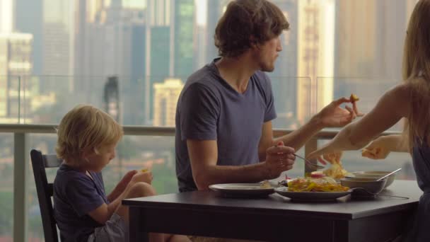 Ung familj med en frukost, lunch på balkongen i en skyskrapa med utsikt på en hela centrum av staden — Stockvideo