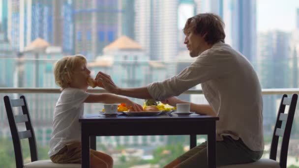 Young family having a breakfast, lunch on their balcony in a skyscraper with a view on a whole downtown of the city — Stock Video