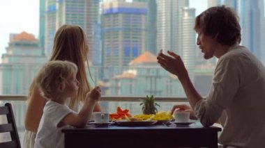 Genç aile bir kahvaltı, Bütün şehir şehir manzaralı bir gökdelen onların balkonda yemek