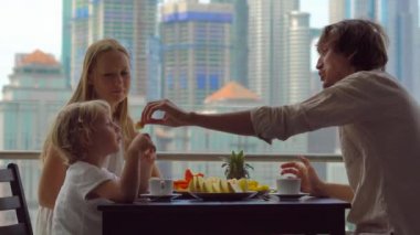 Genç aile bir kahvaltı, Bütün şehir şehir manzaralı bir gökdelen onların balkonda yemek