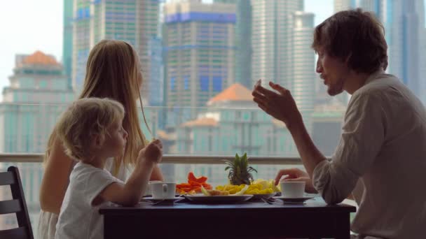 Genç aile bir kahvaltı, Bütün şehir şehir manzaralı bir gökdelen onların balkonda yemek — Stok video