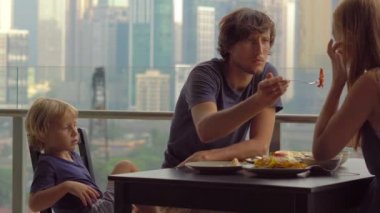 Genç aile bir kahvaltı, Bütün şehir şehir manzaralı bir gökdelen onların balkonda yemek