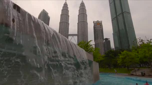 Kuala Lumpur, Malajsie-12. května 2018: Umělý vodopád u bazénu v parku kolem Kulala Lumpur Petronas towers — Stock video