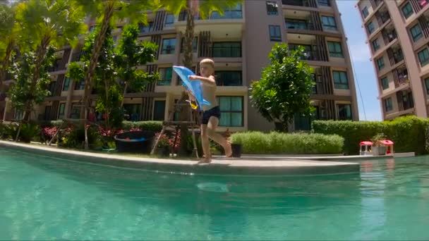 Slowmotion shot z malého chlapce, skákání do bazénu — Stock video