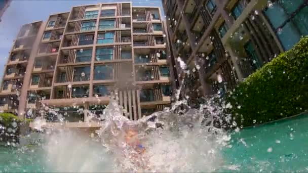 Slowmotion tiro de um pai jogando seu filho na piscina — Vídeo de Stock