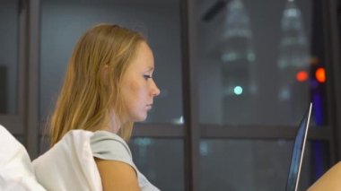 Onun yatağında ısıtmak bir amaç, siluetleri ile oturan bir dizüstü bilgisayar kullanarak çalışan genç kadın