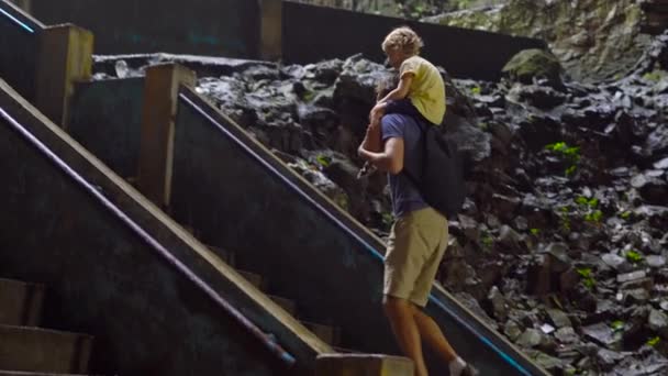 Otec visí jeho syn na ramena, chůzi po schodech uvnitř starověkých Batu jeskyně v Malajsii s hinduistický chrám uvnitř — Stock video