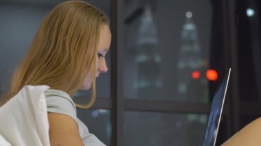 Onun yatağında ısıtmak bir amaç, siluetleri ile oturan bir dizüstü bilgisayar kullanarak çalışan genç kadın