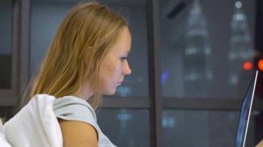 Onun yatağında ısıtmak bir amaç, siluetleri ile oturan bir dizüstü bilgisayar kullanarak çalışan genç kadın