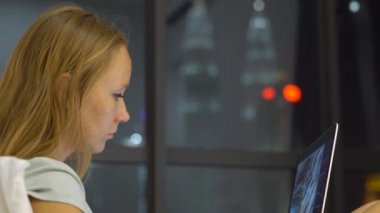 Onun yatağında ısıtmak bir amaç, siluetleri ile oturan bir dizüstü bilgisayar kullanarak çalışan genç kadın