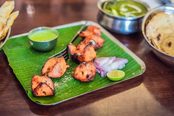 Koyu ahşap arka plan üzerinde çeşitli Hint yemeği. Yemekler ve mezeler Hint Mutfak. Köri, tereyağı tavuk, pirinç, mercimek, paneer, samosa, naan, Hint turşusu, baharatlar. Kase ve Hint yemekleri ile plakalar.