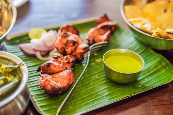 Koyu ahşap arka plan üzerinde çeşitli Hint yemeği. Yemekler ve mezeler Hint Mutfak. Köri, tereyağı tavuk, pirinç, mercimek, paneer, samosa, naan, Hint turşusu, baharatlar. Kase ve Hint yemekleri ile plakalar.