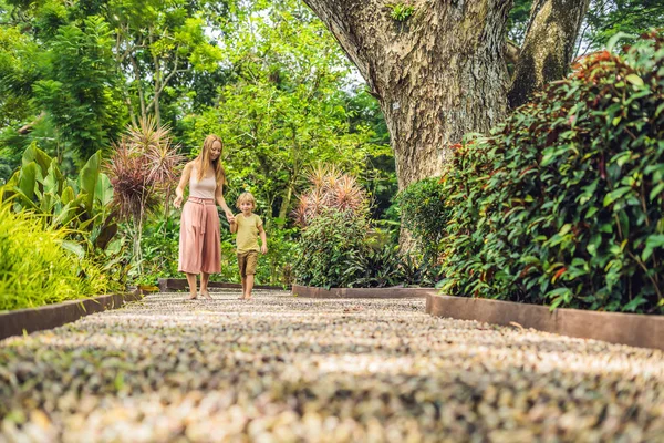 Anne ve oğlu yürümek üstünde A dokulu Arnavut kaldırımı kaplama, refleksoloji. Kaldırımda ayak refleksoloji için çakıl taşları.