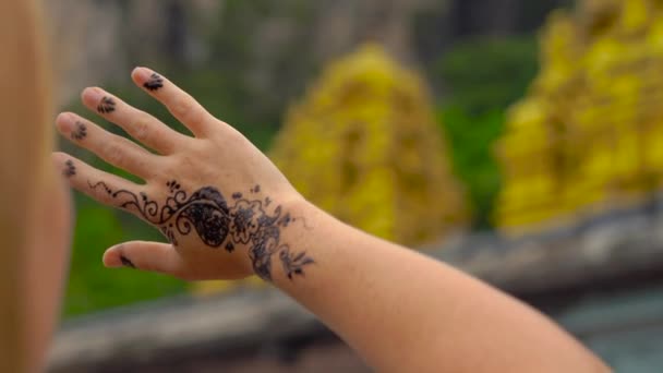 Fiatal nő nézi a kezét egy ideiglenes henna hindu mintával