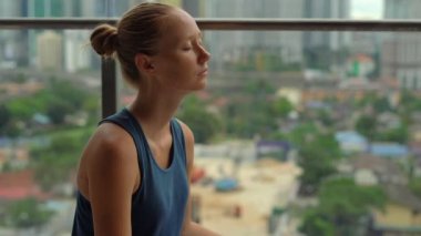 Genç kadın skycrappers ile bir şehir manzaralı balkonunda çok katlı binada Yoga egzersizleri yapıyor. Bir büyük şehir kavram zihinsel denge