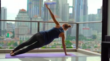 Genç kadın skycrappers ile bir şehir manzaralı balkonunda çok katlı binada Yoga egzersizleri yapıyor. Bir büyük şehir kavram zihinsel denge