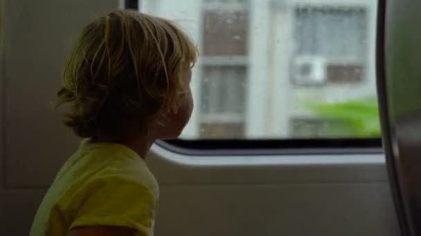 Μικρό αγόρι κάθεται μπροστά από ένα παράθυρο σε ένα κινούμενο τρένο — Αρχείο Βίντεο
