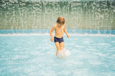 Küçük çocuk yüzme havuzunda eğleniyor.