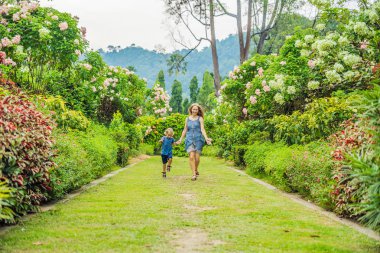 Anne ve oğlu çiçek açan bahçede koşturup. Mutlu aile yaşam tarzı kavramı.