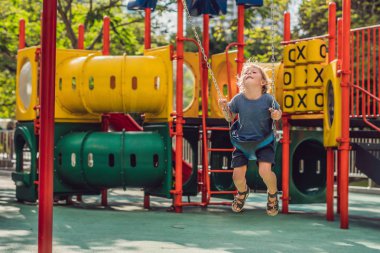 Komik çocuk çocuk açık sahada zinciri salıncak ile eğleniyor. Sıcak gününde sallanan çocuk. Etkin boş çocuklarla. Casual renkli okul çocuk kıyafetleri giyen çocuk.