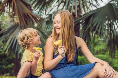 Anne ve oğlu parkta piknik vardı. Sağlıklı meyve - mango, ananas ve kavun yemek. Çocuk sağlıklı yemek yemek.