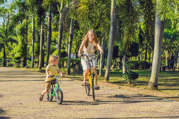 Happy family is riding bikes outdoors and smiling. Mom on a bike and son on a bike.