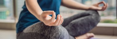 Genç kadın şehir ve gökdelenler panoramik manzaralı balkonunda sabah yoga uygulamak. Başlık uzun biçimi