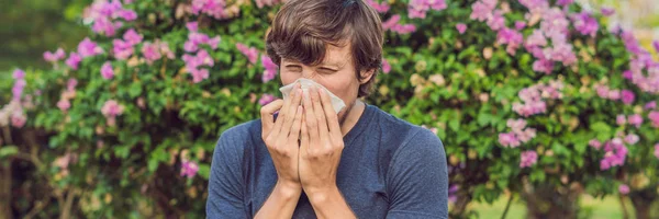 Młody Człowiek Kichnięcie Parku Tle Kwitnących Drzew Alergia Pyłek Koncepcja — Zdjęcie stockowe