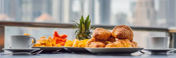 背景には大都市のバルコニーでコーヒー フルーツとパン クロワッサンで朝食用のテーブル バナー長い形式 — ストック写真