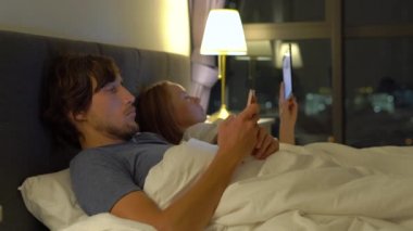 Erkek ve kadın yalan her smartphone ile yatak ve tablet pc. kadın döner lamba ve ve adam yatmamak için gider. Evlilik ve intersexual ilişki sorunları ve mobil sorunları