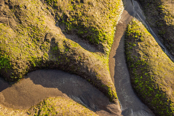 Sea tide on the moss-covered rocky beach, Bali, Indonesia.