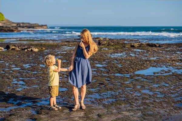 Mom and son walking along cosmic Bali beach. Portrait travel tourists - mom with kids. Positive human emotions, active lifestyles. Happy young family on sea beach.