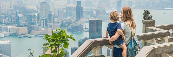 Mom and son travelers at the peak of Victoria against the backdrop of Hong Kong. Traveling with children concept BANNER, long format