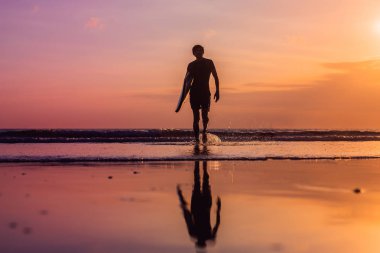 Günbatımında sörf tahtası ev taşıma sörfçü silüeti.