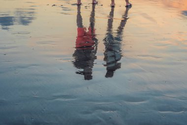 Siluet çift üzerindesin Beach alt gölge ile akşam günbatımında sakin deniz su yüzeyine yansıyan. 