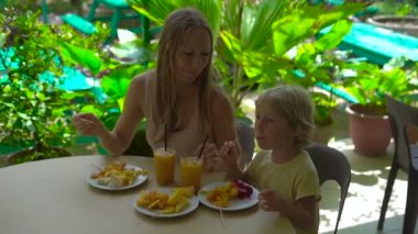 Tropikal meyve yeme ve içme suyu doğal zemin üzerine masada küçük çocuğu olan kadın