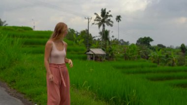 Pirinç tarlaları yakınındaki karayoluyla yürüyen genç kadın