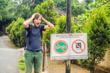Bali, Endonezya - 21 Mayıs 2018: duvar içinde Uber ve kapmak için taksi sürücüleri okuma itiraz Endonezya protesto tabelaya bakarak Genç adam ' Uber ve taksiler girilmez kapmak.