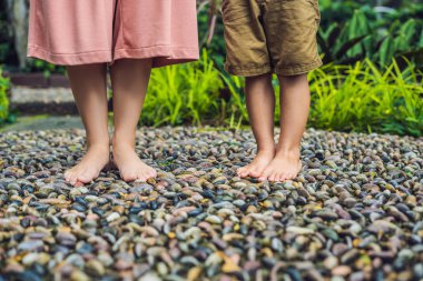 Anne ve oğlu yürümek üstünde A dokulu Arnavut kaldırımı kaplama, refleksoloji. Kaldırımda ayak refleksoloji için çakıl taşları