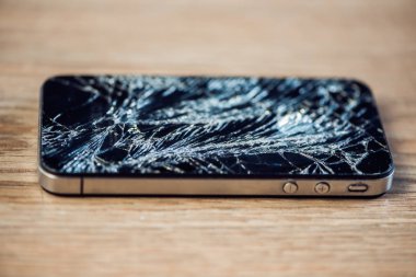 Yünlü bir masada kırık camlı akıllı telefon ekranı..