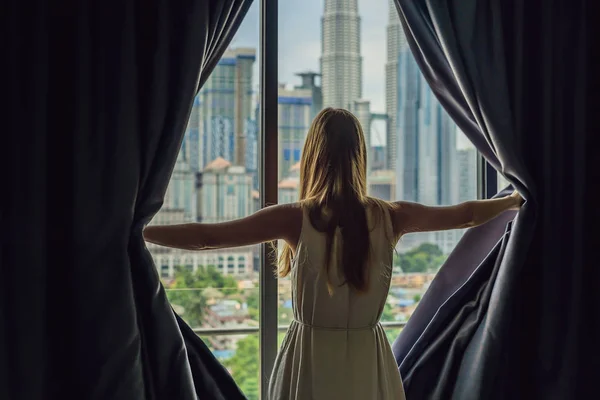 Ung Kvinna Öppnar Fönstret Gardiner Och Ser Skyskrapor Storstaden — Stockfoto