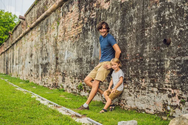 Dad and son on background of Fort Cornwallis in Georgetown, Penang, is a star fort built by the British East India Company in the late 18th century, it is the largest standing fort in Malaysia. Traveling with children concept.