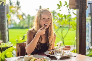 Kadın yeme geleneksel Balinese mutfağı. Sebze ve tofu pilav ile tavada.