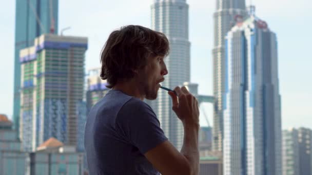 年轻男子刷牙站在窗口附近的城市景观 — 图库视频影像