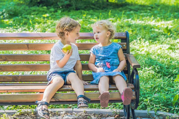 幼児の男の子と女の子の海沿いのベンチに座ってリンゴを食べると — ストック写真