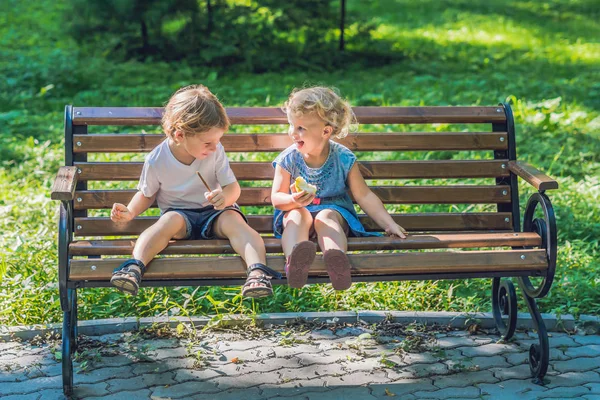 幼児の男の子と女の子の海沿いのベンチに座ってリンゴを食べると — ストック写真