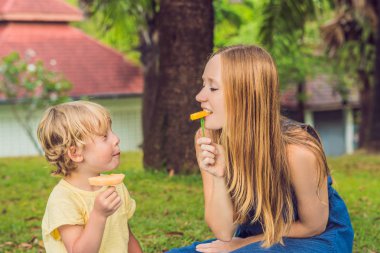 Anne ve oğlu parkta piknik vardı. Sağlıklı meyve - mango, ananas ve kavun yemek. Çocuk sağlıklı yemek yemek.