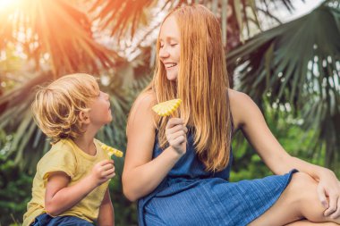 Anne ve oğlu parkta piknik vardı. Sağlıklı meyve - mango, ananas ve kavun yemek. Çocuk sağlıklı yemek yemek.