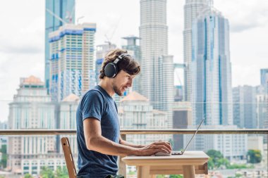 Genç adam bir yabancı dil öğreten ya da büyük bir şehir zemin karşı balkonunda internette yabancı dil öğrenir. Online dil okulu yaşam tarzı.